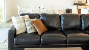 Una sala de estar moderna con un sofá de cuero negro, una mesa de centro de madera y un ventilador de techo.