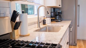 Una cocina moderna con un refrigerador de acero inoxidable, un horno empotrado y un lavamanos.