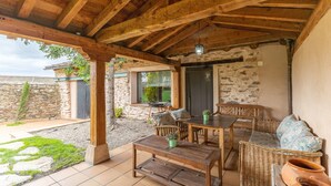 Una veranda riparata con mobili in legno, un muro in pietra e vista sui dintorni.