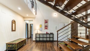 A spacious interior with a wooden staircase, a glass cabinet, and a decorative bench.