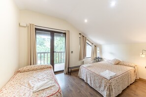 Une chambre avec deux lits, une fenêtre avec des rideaux, un radiateur et un balcon.