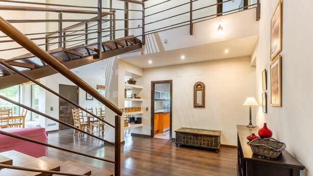 A spacious interior with a wooden staircase, a dining area, and a kitchen.