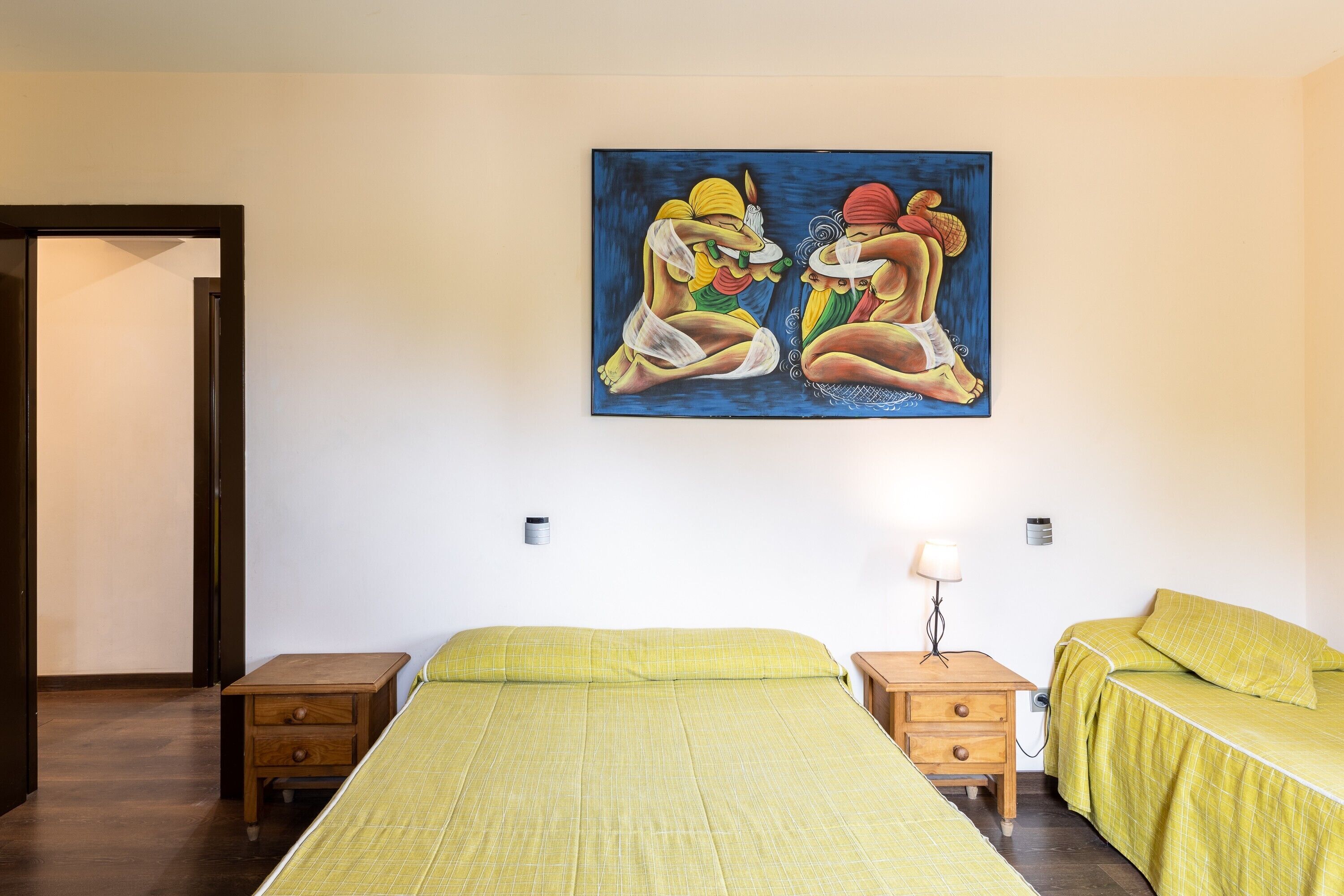 Una habitación con una cama, una mesita de noche, una lámpara y un cuadro en la pared.