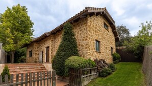 A stone house with a wooden staircase, a fenced yard, and a well-maintained lawn.