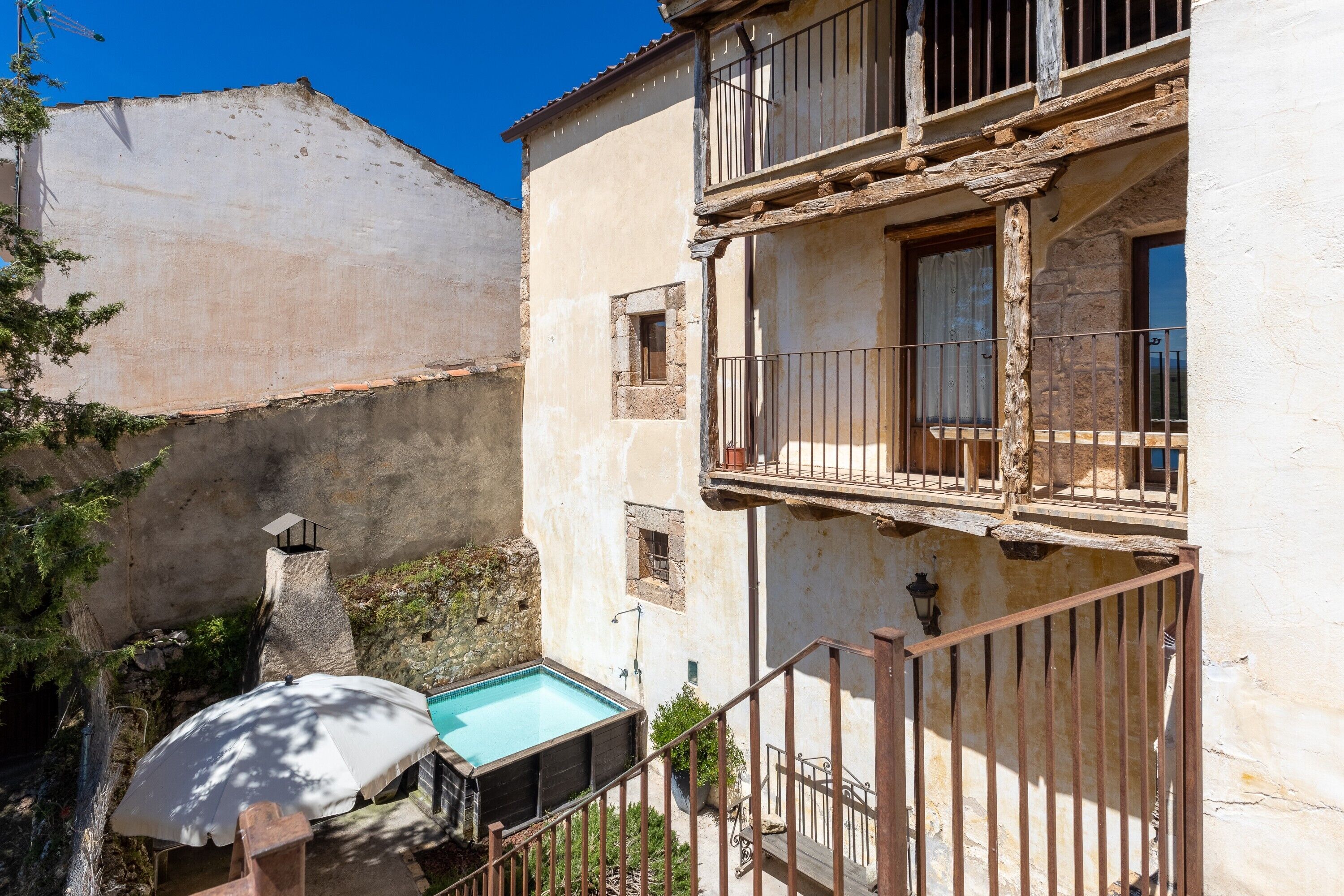 A building with a pool, a balcony, and a stone wall.