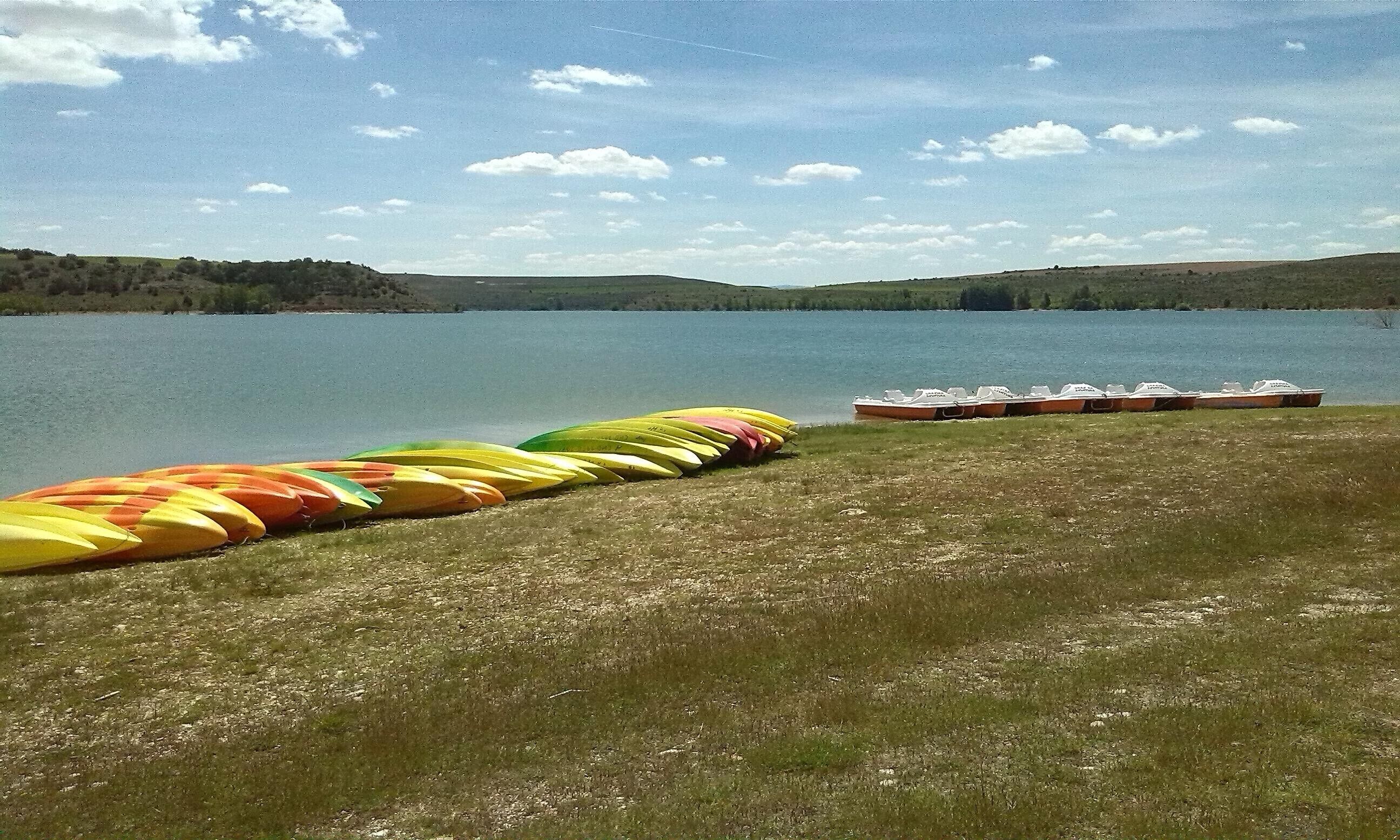 Une vue sur le lac, avec des canoës et des bateaux alignés sur la rive.