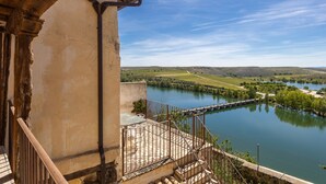 Vista d'un riu amb un pont, un edifici amb un balcó i un cel serè.