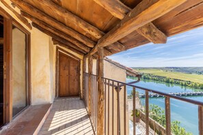 Un balcon en bois offrant une vue sur un lac et des collines.