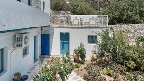 A white building with blue doors and windows, a stone wall, and potted plants.