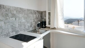 A kitchen with a stone backsplash, a built-in stove, a sink, and a window with a view of the landscape.