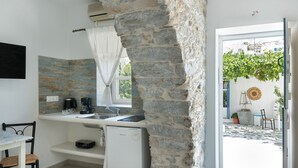Une cuisine compacte avec un mur en pierre, un petit réfrigérateur, une machine à café et un évier.