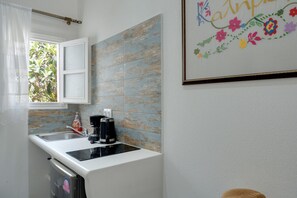 A kitchen with a white countertop, a coffee maker, and a sink.