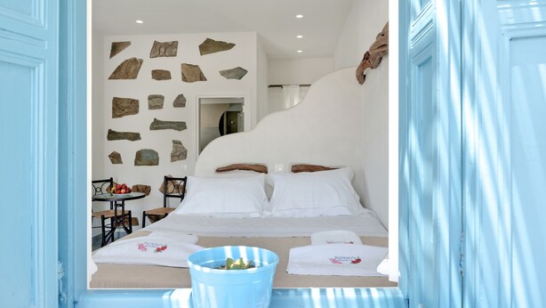 Ein Schlafzimmer mit einem Bett, Kissen, einem blauen Eimer und einem Tisch mit Stühlen.