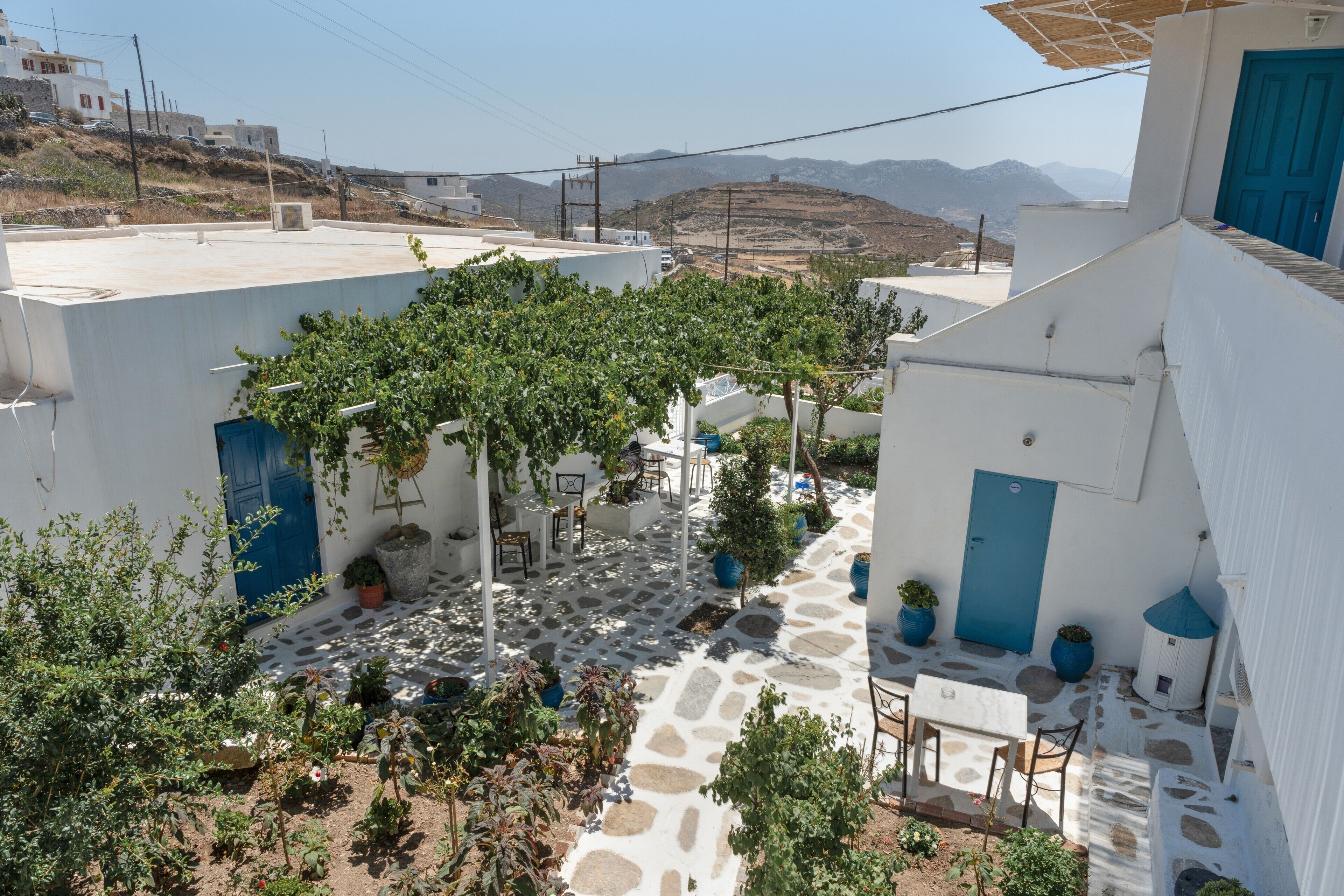 Une cour avec un sol en pierre, des plantes en pot et une porte bleue.