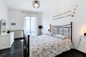 A bedroom with a bed, a dresser, a mirror, a radiator, a window with curtains, and a wall with a motivational quote.