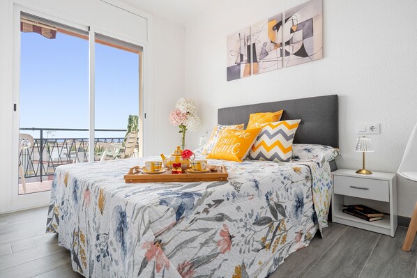 Une chambre avec un lit, une table de chevet, un plateau avec un service à thé et une vue sur le balcon.
