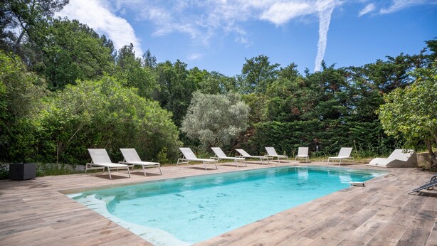 A rectangular swimming pool with a wooden deck, surrounded by trees and white lounge chairs. - Escape and serenity at Studio Le Partegal with shared pool, Wi-Fi and air conditioning (La Valette-du-Var)
