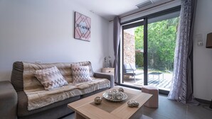 A modern living room with a sofa, a coffee table, and a view of the outdoors. - Escape and serenity at Studio Le Partegal with shared pool, Wi-Fi and air conditioning (La Valette-du-Var)