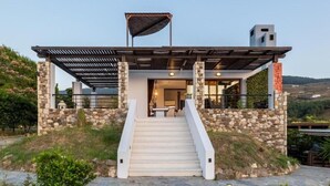 Une maison moderne avec une façade en pierre, une entrée abritée et un escalier menant à la porte.