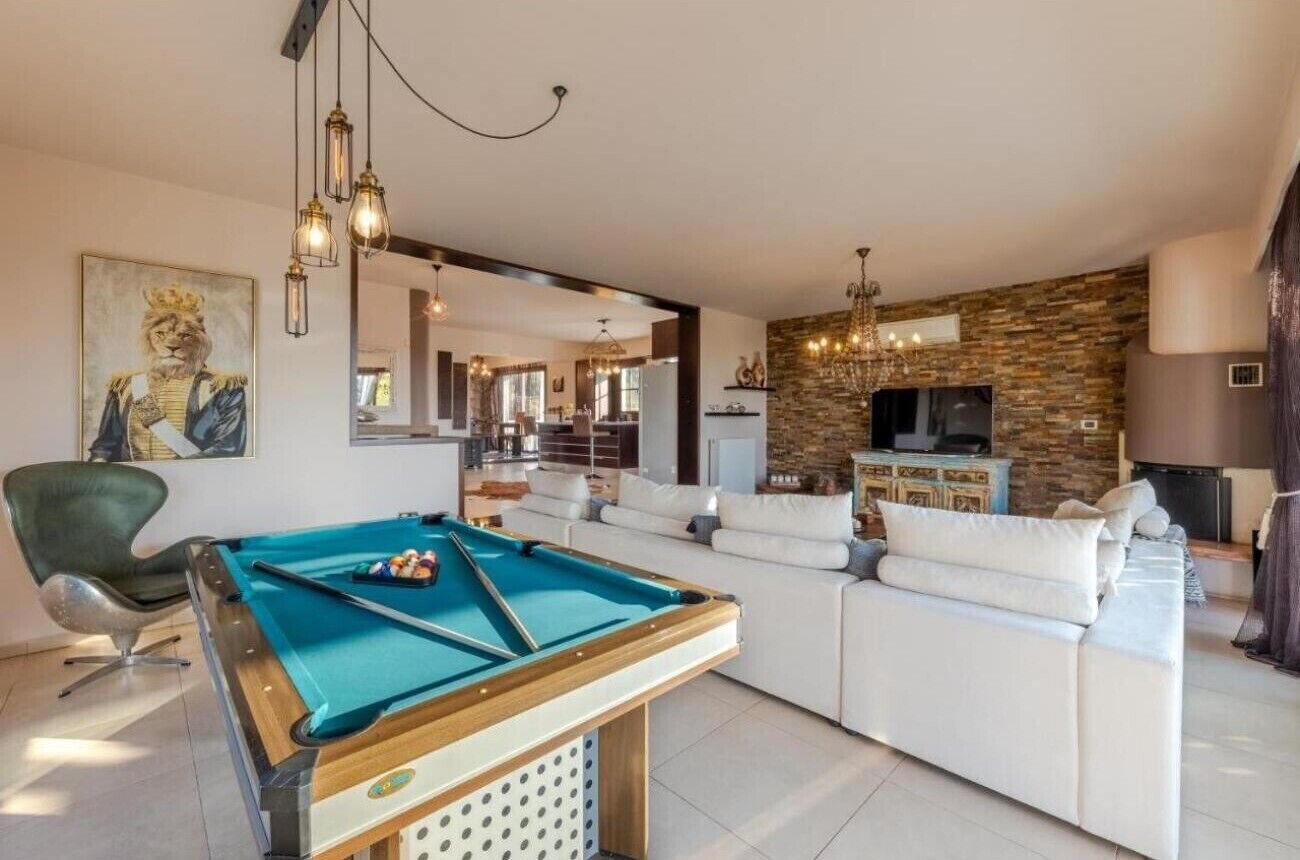 A pool table in a living room with a sofa and a television.