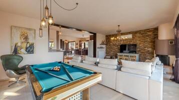 A pool table in a living room with a sofa and a television.