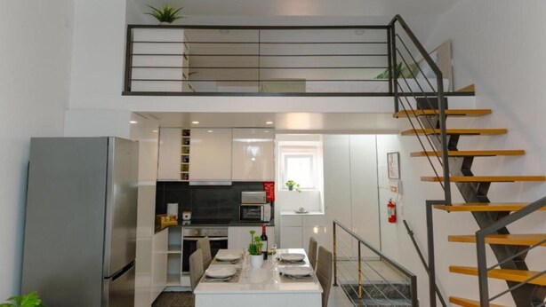 Una cocina moderna con comedor, una escalera y un pequeño balcón.