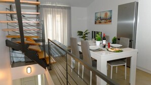 Una cocina moderna con comedor, una escalera y un cuadro de un puente.