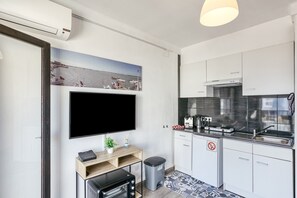 Une cuisine moderne équipée d’un téléviseur à écran plat, d’une machine à café et d’un évier.