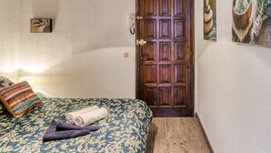 A bedroom with a wooden door, a bed with a floral bedspread, and a wall-mounted picture. - Apartment 'Casa Jois' with Sea View, Wi-Fi and Air Conditioning (Empuriabrava)