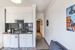 Une cuisine de taille réduite avec des meubles blancs, un plan de travail noir et une machine à café.