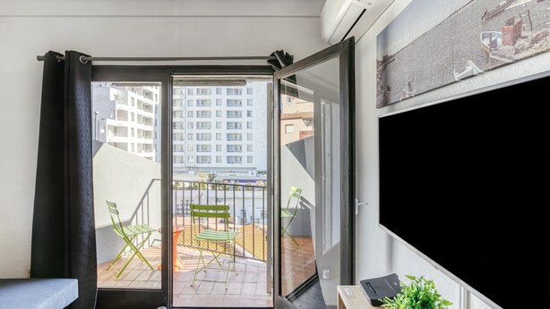 A balcony with a view of a building, a chair, and a small table with a plant. - Apartment 'Casa Jois' with Sea View, Wi-Fi and Air Conditioning (Empuriabrava)