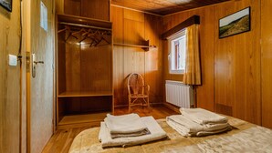 Une pièce en bois avec un lit, une chaise et une armoire.