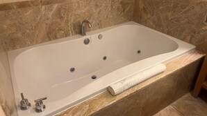 Un baño moderno con una bañera independiente, azulejos de mármol y un perchero para toallas.