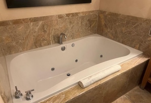 Experience ultimate relaxation in this bathroom, featuring a large bathtub with multiple faucets and a control knob for customizable comfort.