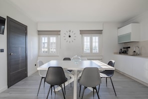 A modern dining area with a white table, black chairs, a glass dome light, and a wall clock. - Holiday Home 'A Neida Con Vistas Al Mar' with Sea View, Private Terrace and Wi-Fi (Cee)