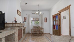 A living room with a fireplace, a dining area with a table and chairs, and a sofa. - Holiday Home 'Villa Sheyla Maria' with Private Pool, Private Terrace and Air Conditioning (Conil de la frontera)
