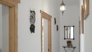 A hallway with a wooden door, a wall-mounted zebra head sculpture, a mirror, and a wall-mounted light fixture. - Holiday Home 'Villa Sheyla Maria' with Private Pool, Private Terrace and Air Conditioning (Conil de la frontera)