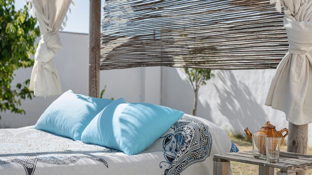 A bed with blue pillows, a patterned bedspread, a wicker headboard, and a small table with a teapot and glasses. - Holiday Home 'Villa Sheyla Maria' with Private Pool, Private Terrace and Air Conditioning (Conil de la frontera)