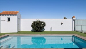 A swimming pool with a tiled deck, a small window, and a white wall with a tiled roof. - Holiday Home 'Villa Sheyla Maria' with Private Pool, Private Terrace and Air Conditioning (Conil de la frontera)
