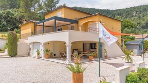 A two-story building with a balcony, potted plants, and a flag. - Apartment 'Lobéal' with Shared Pool, Wi-Fi and Air Conditioning (Auriol)