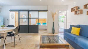 A modern living room with a sofa, coffee table, and a dining area with chairs and a table. - Apartment 'Lobéal' with Shared Pool, Wi-Fi and Air Conditioning (Auriol)
