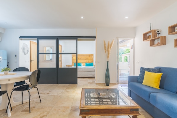 A modern living room with a sofa, coffee table, and a dining area with chairs and a table.
