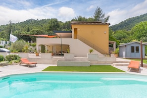 A pool area with lounge chairs, a staircase, and a flag.