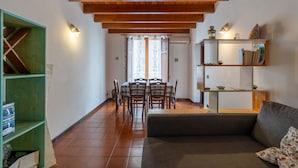 A dining area with a wooden ceiling, a green shelf unit, and a sofa with a cushion. - Apartment 'Antiche Scale' with Mountain View, Wi-Fi and Air Conditioning (Castellammare del Golfo)