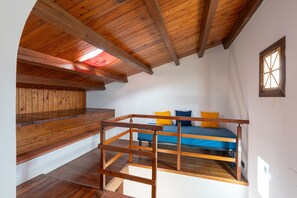 Een slaapkamer in een loft met een houten plafond, een stapelbed en een klein raam.