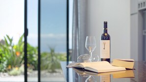 A table with a wine bottle, a wine glass, and two books. - Holiday Home 'Refugio Do Lourinho' with Sea View, Wi-Fi and Air Conditioning (Calheta)