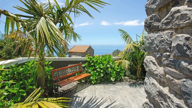 A stone wall, a bench, and lush greenery with a view of the sea. - Holiday Home 'Refugio Do Lourinho' with Sea View, Wi-Fi and Air Conditioning (Calheta)