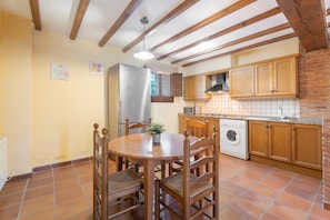 Una cocina con armarios de madera, lavadora y mesa de comedor con sillas.