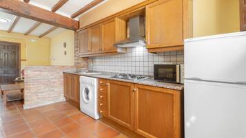 Une cuisine avec des meubles de rangement en bois, un lave-linge, un four à micro-ondes et un réfrigérateur.