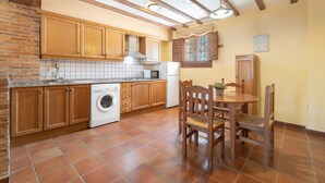 Una cocina con armarios de madera, una lavadora y un comedor con mesa y sillas.
